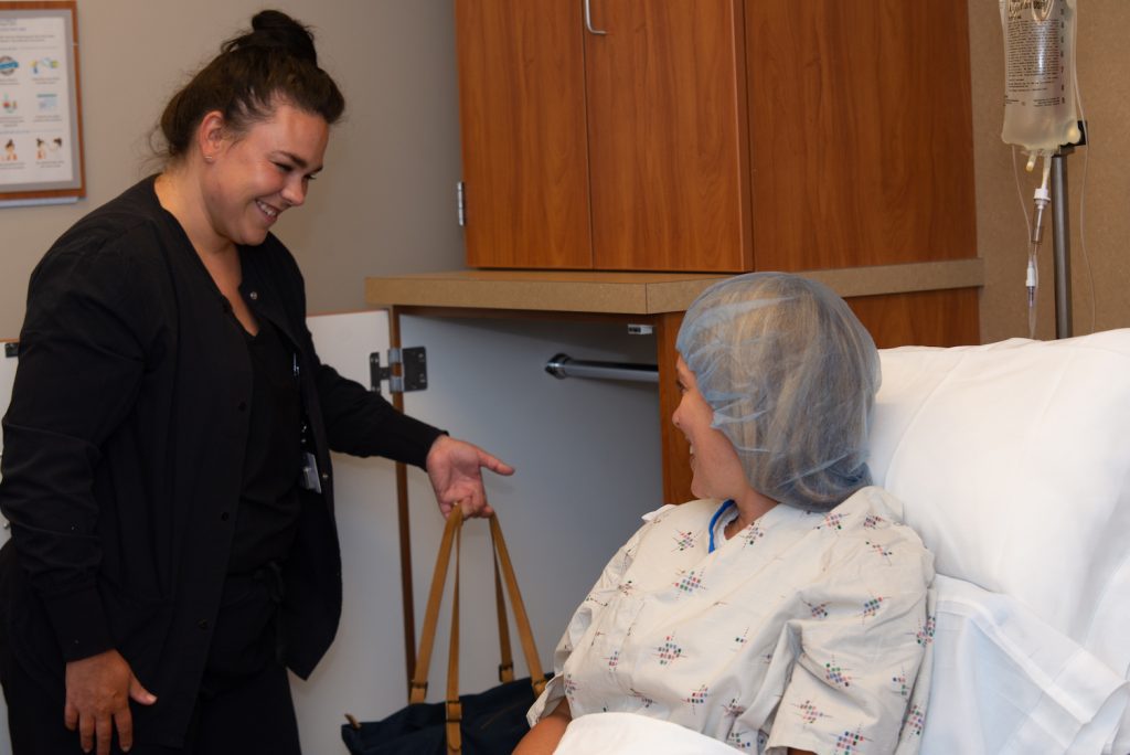 female nurse helping a patient by putting her bag in a closest before surgery