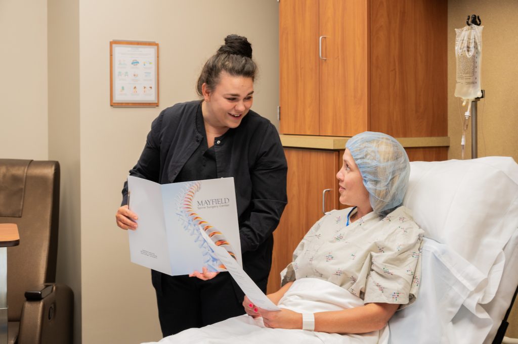 female nurse going over documents with a female patient who is sitting in a hospital bed