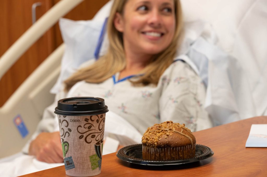 cup of coffee and muffin on a table with a female patient in the back at a spine surgery center